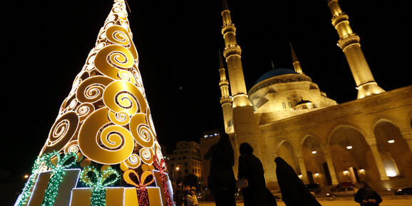 Residents stand near a Christmas tree in front of the Al-Amin mosque in downtown Beirut